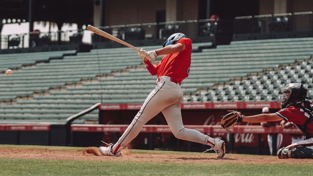 A baseball player in a red jersey swinging a bat at a ball