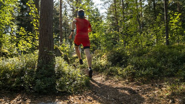 a man in red running through a forest