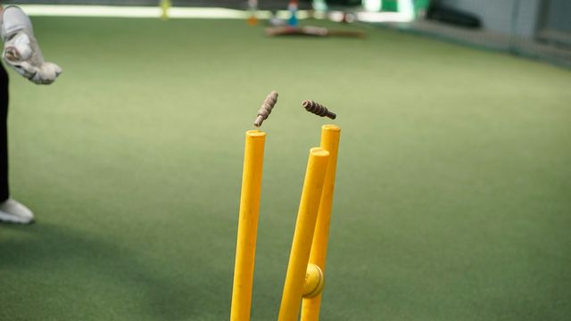 A man standing next to a yellow bat and ball